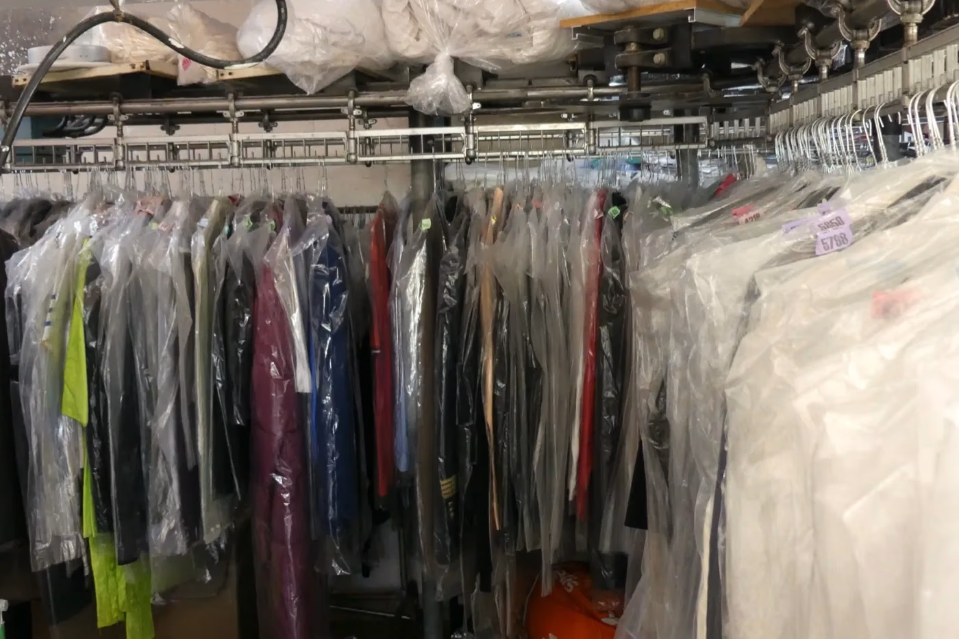 Convoyeur de l'atelier Belle Allure, vêtements nettoyés et protégés sous housse
